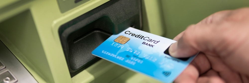 يد رجل تحمل بطاقة ائتمان باستخدام رجل صراف آلي يستخدم ماكينة صراف آلي ببطاقته الائتمانية